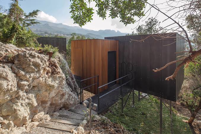 Los módulos de madera escalonados sobre la ladera, con la sierra de Aitana al fondo
